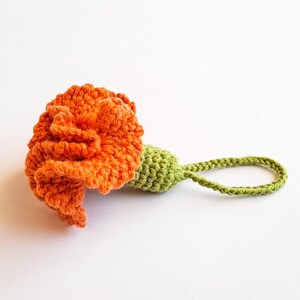 Crochet carnation keychain with frilled orange petals and green base, made with cotton yarn – PDF pattern project.