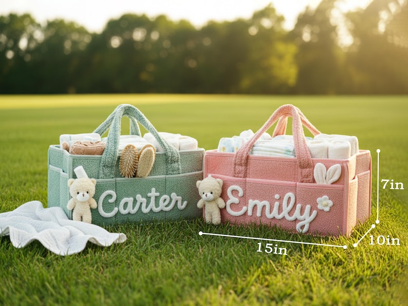 May include: Two personalized baby caddies, one green and one pink, sit on grass. The green caddy, labeled "Carter," holds baby supplies. The pink caddy, labeled "Emily," also holds baby supplies. Each caddy is 15 inches long, 10 inches wide, and 7 inches tall.