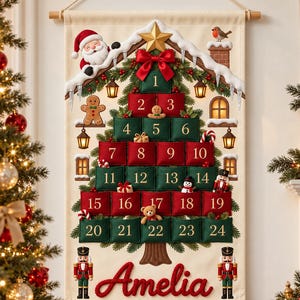 Könnte beinhalten: Ein hängender Weihnachts-Adventskalender aus Stoff in Tannenbaumform mit nummerierten Taschen von 1 bis 24 in Rot und Grün. Er ist mit einem Weihnachtsmann, Lebkuchenmann, Schneemann und Nussknackern verziert und trägt den Namen Amelia in roter Schrift.