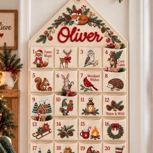 May include: A cream-coloured fabric advent calendar shaped like a house with the name Oliver in red script at the top. It features twenty-four numbered pockets, each decorated with colourful illustrations of woodland animals, holiday greenery, and gifts.