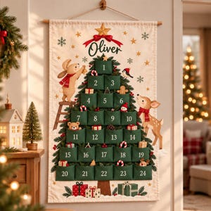 Peut inclure: Un calendrier de l'Avent mural en tissu représentant un sapin de Noël avec vingt-quatre poches vertes numérotées. Le motif inclut un lapin, un cerf et le nom Oliver en haut, agrémenté d'une étoile dorée et d'un ruban rouge.