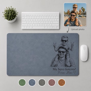 May include: A blue rectangular mouse mat featuring a black and white illustration of a father and son. The text "My hero forever! From Ben" is below the illustration. A white keyboard and mouse are also present.