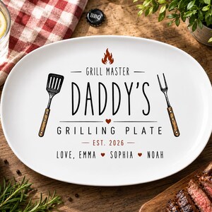 Peut inclure: Assiette ovale blanche pour barbecue avec le texte "Grill Master Daddy's Grilling Plate" et les noms Emma, Sophia et Noah. L'assiette a un dessin de spatule et de fourchette.