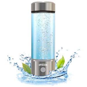 May include: A cylindrical water bottle with a silver cap and base. The clear glass body contains blue liquid with bubbles. The base has a button and the brand name "NXXCER". Water splashes and green leaves surround the bottle.