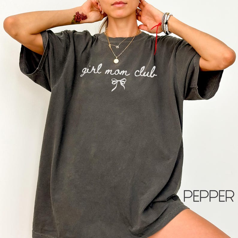 Peut inclure: Un t-shirt surdimensionn&eacute; gris fonc&eacute; avec le texte "girl mom club" et un petit n&oelig;ud brod&eacute; en blanc sur le devant.