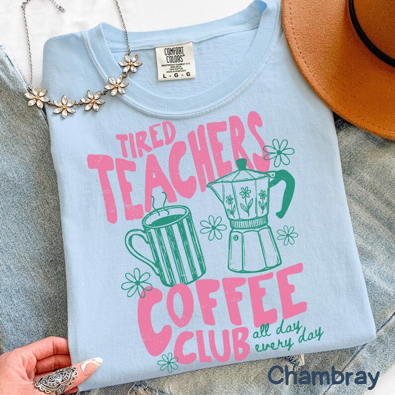 May include: Light blue t-shirt with the text "Tired Teachers Coffee Club" in pink and green. The design includes a coffee cup, a coffee pot, and flowers. The shirt is a Comfort Colors brand.