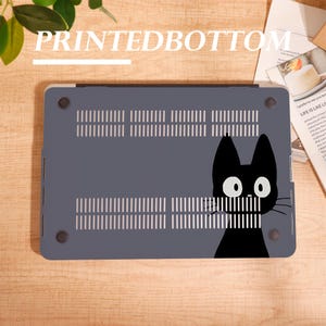 May include: A gray laptop case featuring a black cat graphic on the bottom. The case has ventilation slots and the text "PRINTEDBOTTOM" at the top. The cat has large white eyes and a simple, stylized design.