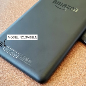 May include: Black tablet device with the Amazon logo and the text "MODEL NO: SV98LN". The device has rounded corners and a smooth, matte finish. The model number is also printed on a small sticker.