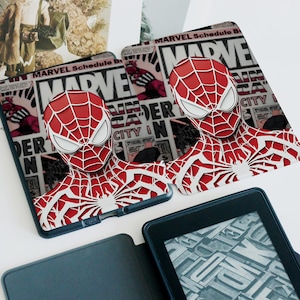 May include: Two red and white Spider-Man themed tablet cases. The cases feature a 3D design of Spider-Man's head and torso. The background of the cases has a comic book style design with the word "MARVEL" and other text.