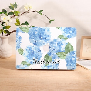 May include: A laptop case featuring a watercolor design of blue hydrangea flowers and green leaves on a white background. The name "Nathaniel" is written in a cursive font across the bottom.