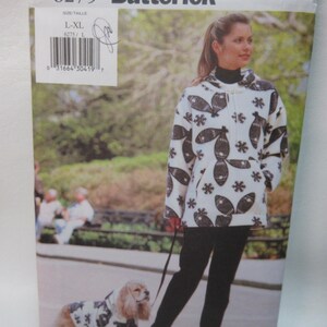 May include: A white and black patterned hooded sweater with a zipper closure. The model is wearing black pants and walking a dog wearing a matching sweater. The pattern on the sweater features black fish and snowflakes. The image includes the text "6275 Butterick" and "L-XL 6275/L".