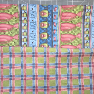 May include: Two pieces of fabric. The top piece is blue and green with a repeating pattern of pink cats, coffee cups, and the text "A Java Cat Java Cat". The bottom piece is a green, blue, and red plaid.