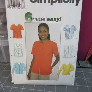 May include: Simplicity sewing pattern featuring a woman in an orange top. The pattern includes multiple shirt designs, with the text "6 made easy!" and size information.
