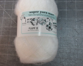 May include: A white ball of yarn labeled "super yarn mart!" and "FLUFF II 100% ACRYLIC FIBERS".