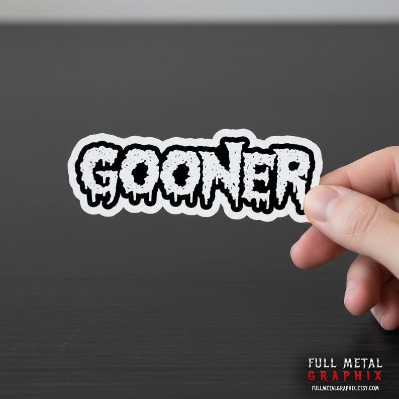 May include: A white sticker with the word "GOONER" in a dripping, textured font. The sticker is held by a hand against a dark background. The bottom right corner features the text "FULL METAL GRAPHIX" and a website address.