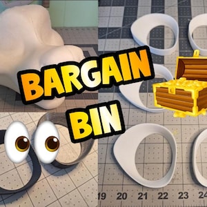 May include: The image showcases various craft supplies and tools. Included are white, oval-shaped pieces, a large white foam shape, and a black ring. The text "BARGAIN BIN" is prominently displayed in a yellow and orange banner.