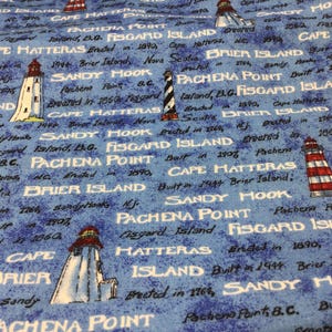 May include: Blue fabric with a lighthouse pattern. The fabric features various lighthouse designs in white, red, and black, along with text mentioning locations like Cape Hatteras and Sandy Hook.