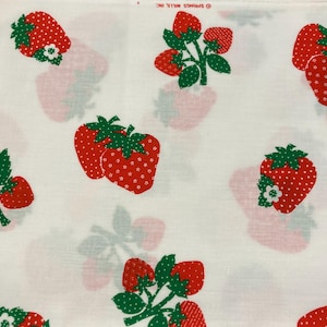 May include: A white fabric featuring a repeating pattern of red strawberries with green leaves and small white flower accents. The strawberries are depicted in various clusters and orientations. The text SPRINGS MILLS, INC is printed at the top.