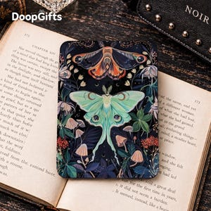 May include: A rectangular e-reader cover featuring a dark background with a large, pale green luna moth and a smaller, orange-patterned moth above it. The design includes various mushrooms, foliage, and small white flowers surrounding the moths.