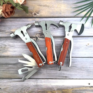 May include: Three multi-tool hammers with wooden handles and silver metal components. One hammer has a variety of folding tools, another has a claw hammer, and the third has a small axe head. The word "Maddy" is engraved on one of the tools.