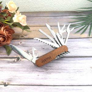 May include: A multi-tool with a wooden handle and various stainless steel implements, including a knife, saw, and bottle opener. The handle is engraved with the name "Maddy".