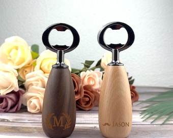 May include: Two bottle openers with a dark metal opener and a wooden handle. One handle is dark brown with an "M" and laurel wreath design. The other is light wood with the name "JASON" and a mustache. The openers are set against a floral background.