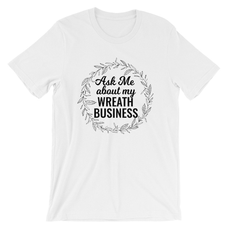 Peut inclure: T-shirt blanc avec un motif de couronne noire et le texte "Ask Me about my WREATH BUSINESS".