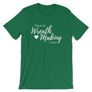 May include: A green t-shirt with white text that says "This is my Wreath Making T-Shirt" with a white heart symbol.
