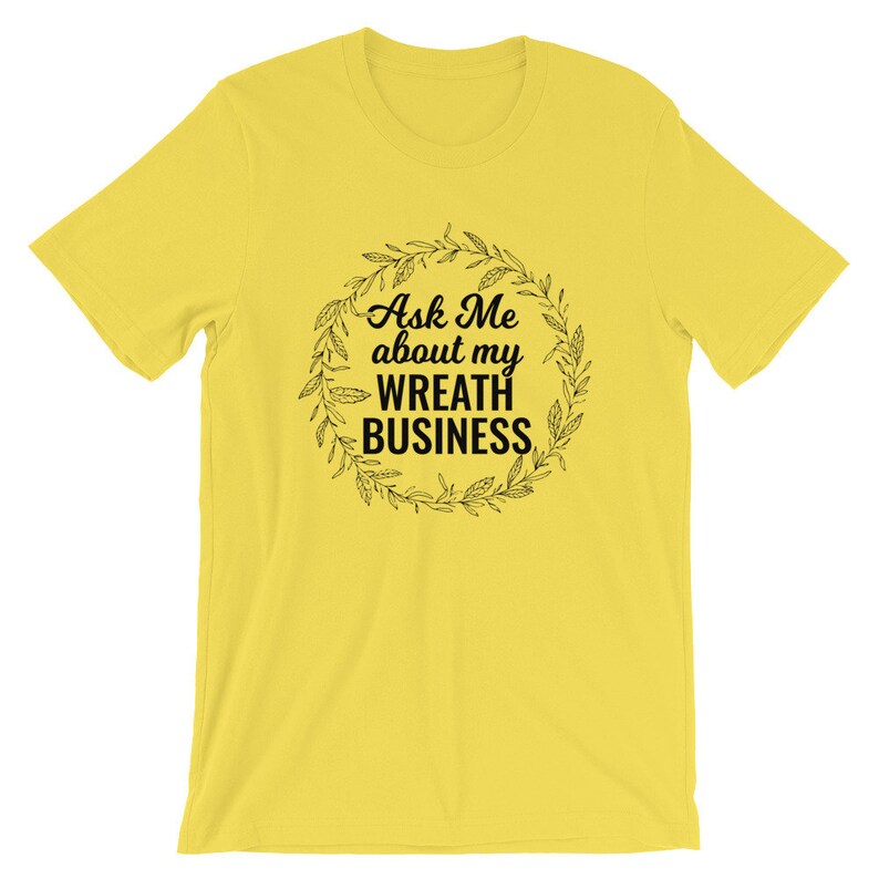 Peut inclure: T-shirt jaune avec un motif de couronne noire et le texte "Ask Me about my Wreath Business".