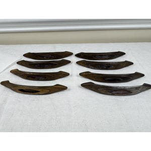 May include: Eight curved drawer pulls arranged in two columns. Each pull features a dark brown wood-grain finish with a smooth, elongated oval center inlay in a deep purple hue. The hardware has a sleek, arched shape with tapered ends.