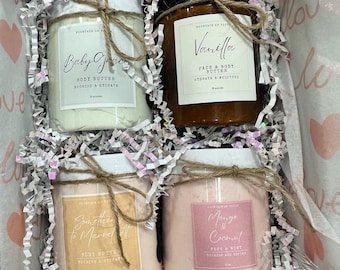 May include: A gift box filled with four jars of body butter. The jars are labeled "Baby Grace", "Vanilla", "Something to Marvel At", and "Mango & Coconut".