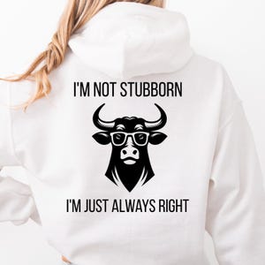 Può includere: Felpa con cappuccio bianca con grafica di un toro nero con occhiali. Il testo "I'M NOT STUBBORN" è sopra il toro e "I'M JUST ALWAYS RIGHT" sotto. La felpa con cappuccio è realizzata in materiale morbido.