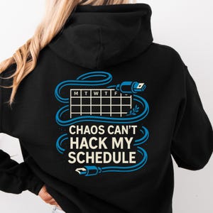 Può includere: Felpa con cappuccio nera con grafica blu e bianca. La grafica presenta un calendario, un design a cavo del computer e il testo "CHAOS CAN'T HACK MY SCHEDULE". La felpa ha un cappuccio e una tasca frontale.