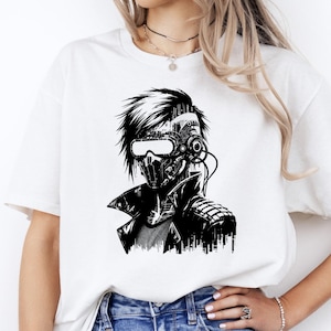 May include: White t-shirt featuring a black and white illustration of a futuristic figure with a mechanical mask, goggles, and a jacket. The graphic design has a cyberpunk aesthetic, with detailed mechanical elements and a stylized cityscape.