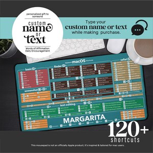 May include: A rectangular desk mat featuring a teal background with white and coloured text displaying over 120 macOS keyboard shortcuts. The mat includes sections for basic, finder, screenshot, safari, and text editing commands, with the name MARGARITA printed.