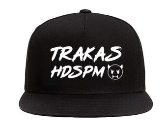 May include: Black and white baseball cap with the text "TRAKAS HDSPM" and a small devil face graphic.