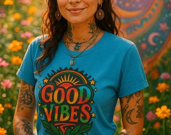 May include: A person wearing a blue t-shirt with the words "GOOD VIBES" in a colorful, retro design. The person is in a field of flowers, with a colorful mural in the background. They are wearing jewelry and have tattoos.