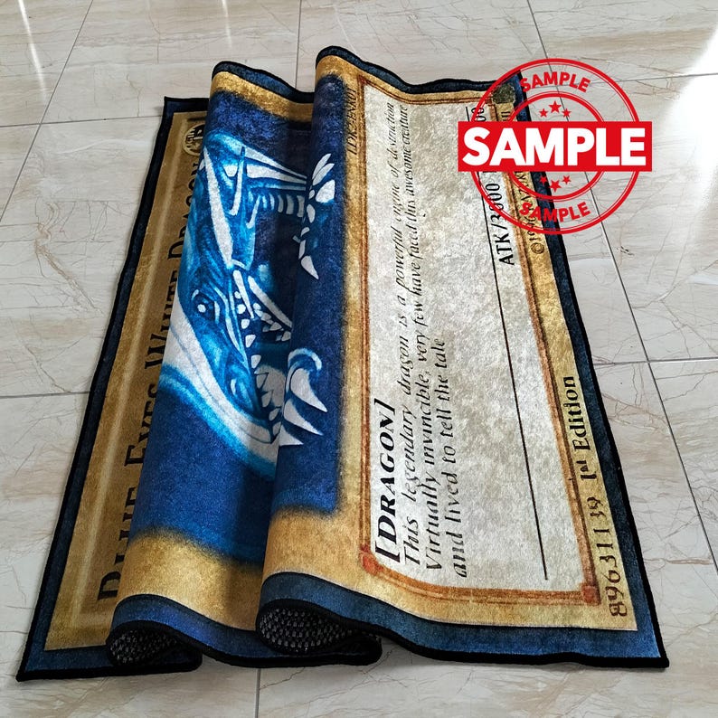 Może przedstawiać: Zwinięty dywan z niebiesko-białym wzorem smoka i napisem "Blue Eyes White Dragon". Dywan ma złotą obw&oacute;dkę, a słowo "SAMPLE" jest wytłoczone w prawym g&oacute;rnym rogu.