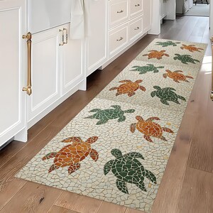 May include: A rectangular runner rug with a mosaic tile design. The rug features a pattern of sea turtles in shades of green and orange against a cream-colored background. The rug is placed on a hardwood floor.