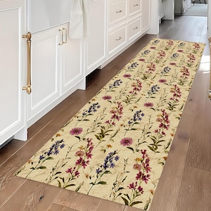 May include: A rectangular floral runner rug with a cream backdrop, showcasing a repeating pattern of purple, pink, and blue flowers with green stems. The rug is on a wooden floor.