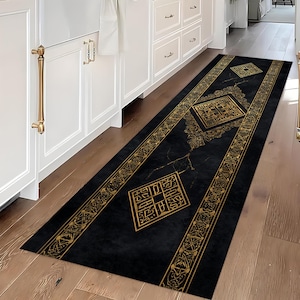 Könnte beinhalten: Ein langer, rechteckiger schwarzer Teppich mit goldenen geometrischen Mustern und Designs. Der Teppich hat eine zentrale Diamantenform und Bordüren mit sich wiederholenden Mustern. Der Teppich liegt auf einem Holzboden in einer Küche.