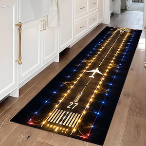 May include: A long rectangular runner rug featuring a high-contrast graphic print of an airport runway at night. The design includes a white airplane silhouette, the number 27, and rows of glowing yellow and blue lights against a dark background.