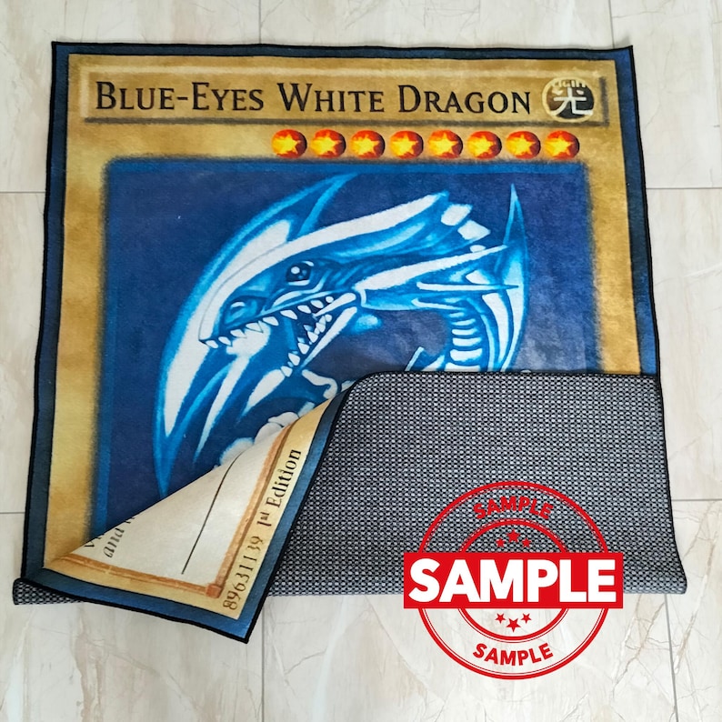 Może przedstawiać: Prostokątny dywan z "Blue-Eyes White Dragon" z kolekcjonerskiej gry karcianej Yu-Gi-Oh!. Dywan ma ilustrację niebieskiego smoka na niebieskim tle, z tekstem i symbolami gwiazd karty. Dywan jest prostokątny z czarną obw&oacute;dką.