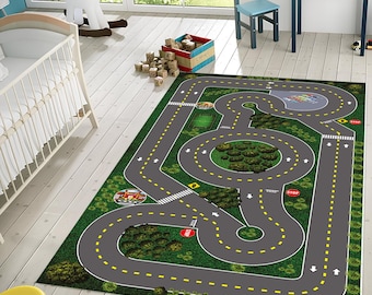 May include: A green and gray play rug with a road track design. The rug features yellow lines, stop signs, and arrows. There are small toy cars on the road.