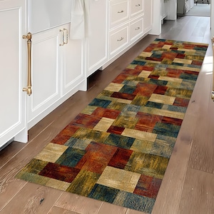 May include: A rectangular runner rug with a geometric pattern in shades of red, blue, gold, and brown. The rug features a repeating square design with a textured appearance, suitable for a kitchen or hallway.