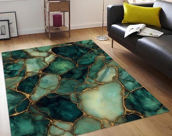May include: A rectangular area rug with a marble-like design. The rug features shades of green and teal with gold-colored veining. The rug is placed on a hardwood floor, and a black sofa and window are visible in the background.