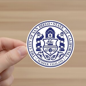 May include: A round sticker featuring the official seal of the City of San Diego, California. The design is in navy blue and white, with the text "THE CITY OF SAN DIEGO • STATE OF CALIFORNIA" encircling the seal. The seal includes a ship, bell, and the motto "SEMPER VIGILANS."