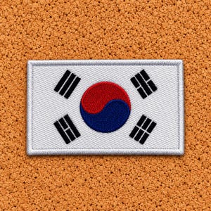 May include: A rectangular embroidered patch featuring the South Korean flag. The design includes a central red and blue taegeuk symbol surrounded by four black trigrams on a white background, all enclosed within a stitched silver border.