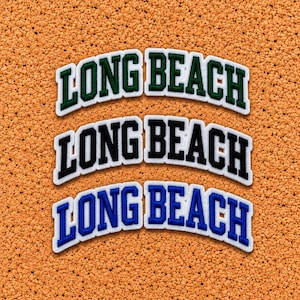 May include: Three arched embroidered patches featuring the text LONG BEACH in block lettering. The top patch has dark green letters with a white border, the middle has black letters with a white border, and the bottom has blue letters with a white border.