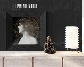 Op de afbeelding: Een zwart ingelijste print van een vrouwengezicht met een hemels ontwerp, een klein zwart Boeddhabeeldje en een witte lamp op een licht houten plank met de tekst "FRAME NOT INCLUDED".